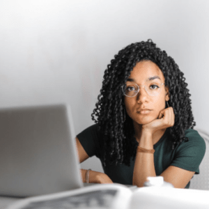 Woman at laptop with chin on hand